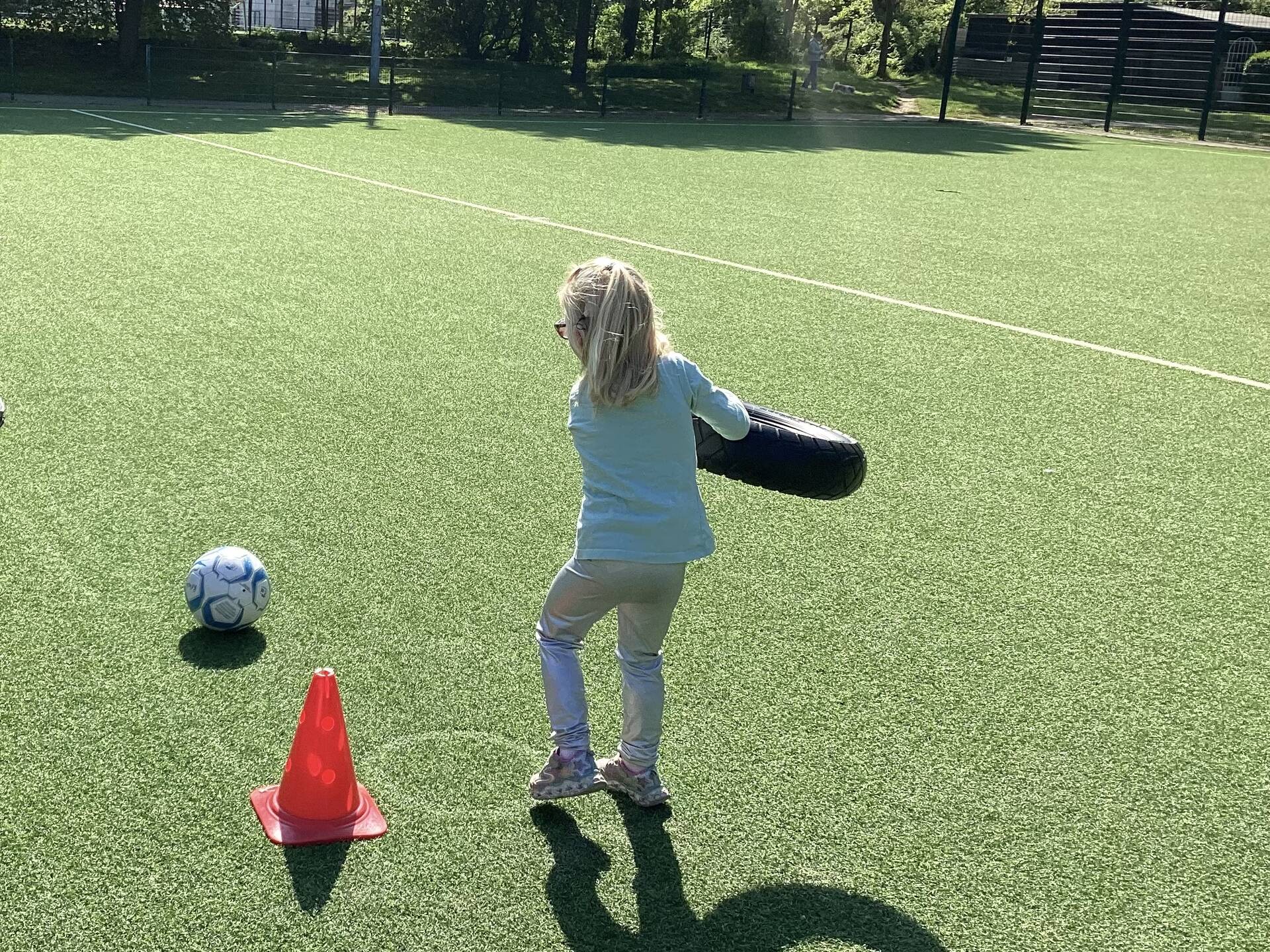 Ein Kind hat einen Reifen in der Hand und befindet sich auf einem Fussballplatz