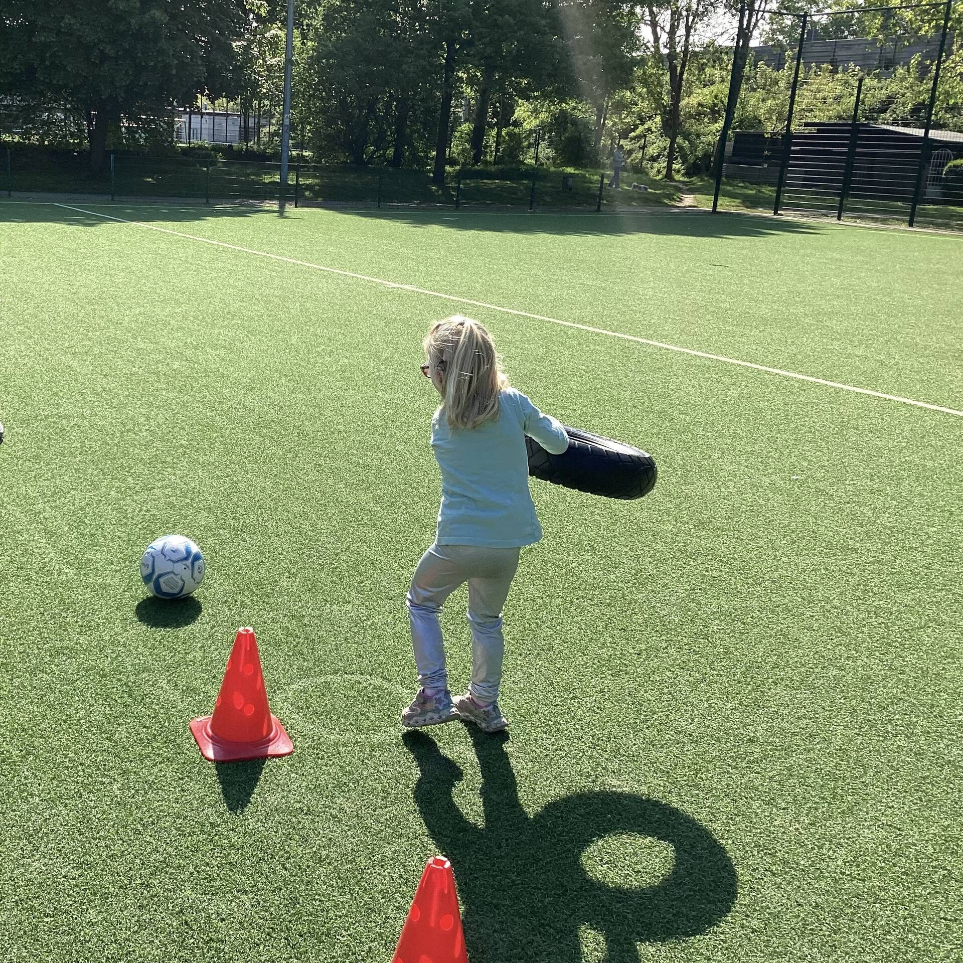 Ein Kind hat einen Reifen in der Hand und befindet sich auf einem Fussballplatz