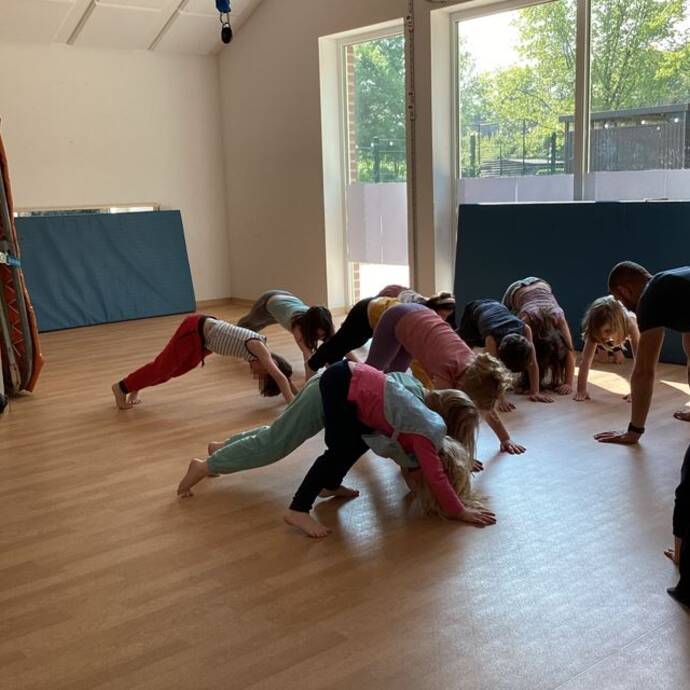 Mehrere Kinder machen eine Übung auf dem Fussboden