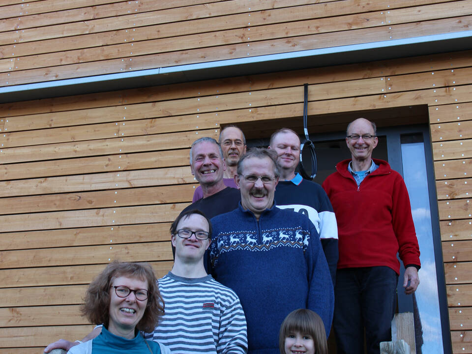 Mehrere Personen stehen auf einer Treppe und ein Kind winkt.