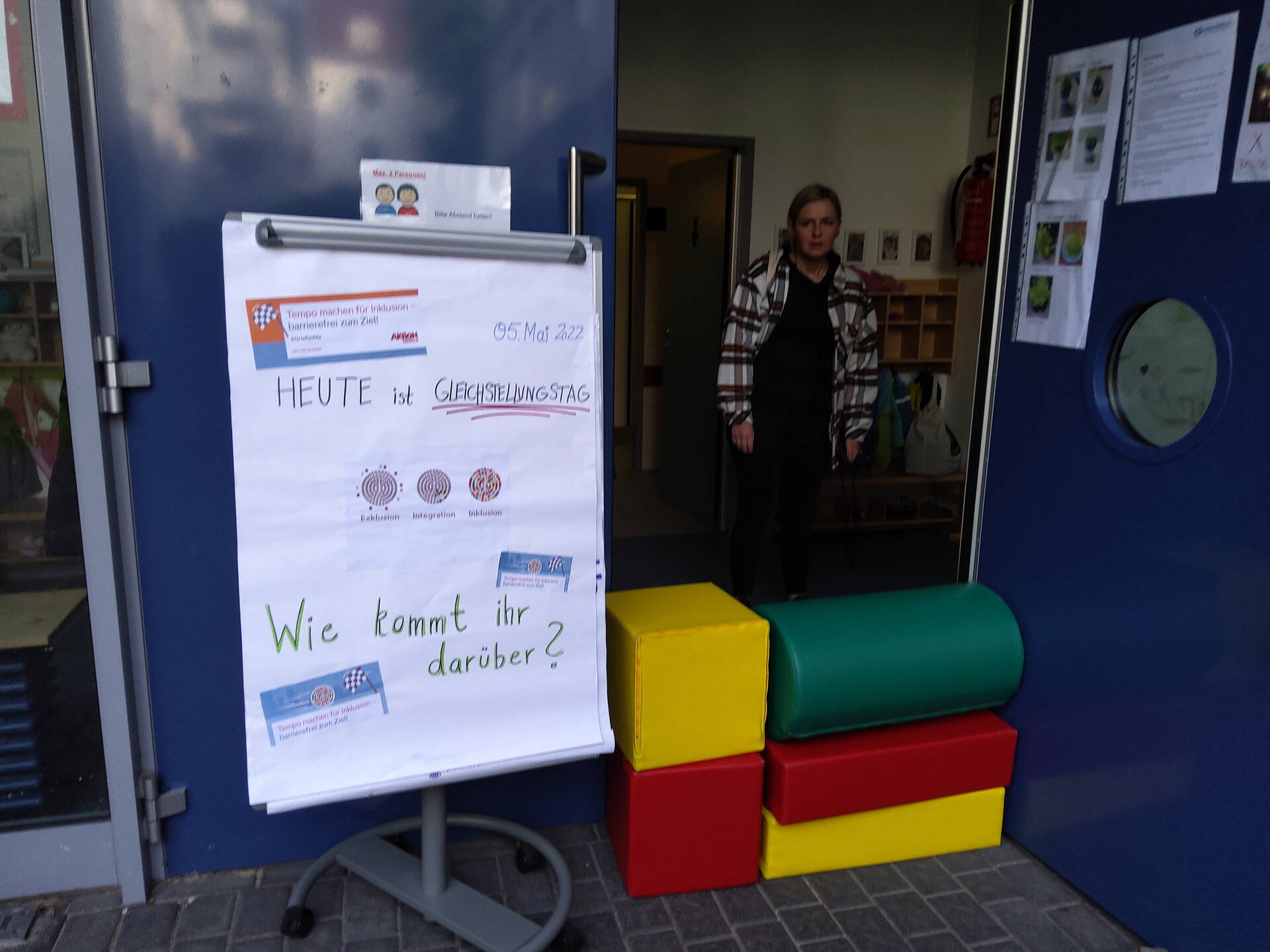 Eine Person hinter großen Bausteinen und einem Flipchart