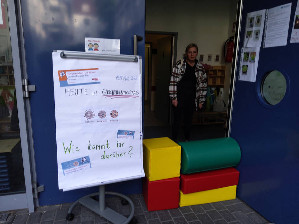 Eine Person hinter großen Bausteinen und einem Flipchart
