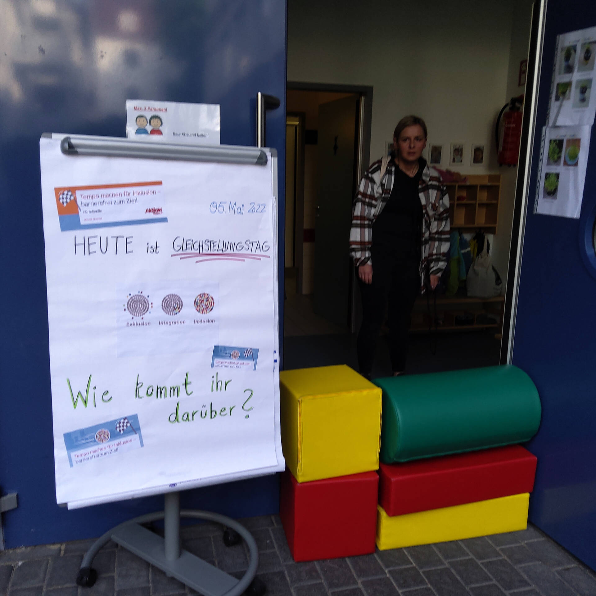 Eine Person hinter großen Bausteinen und einem Flipchart
