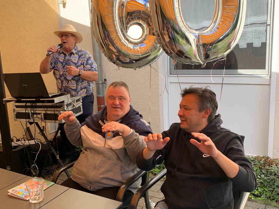 Zwei Personen halten Ballons in Form einer 60.