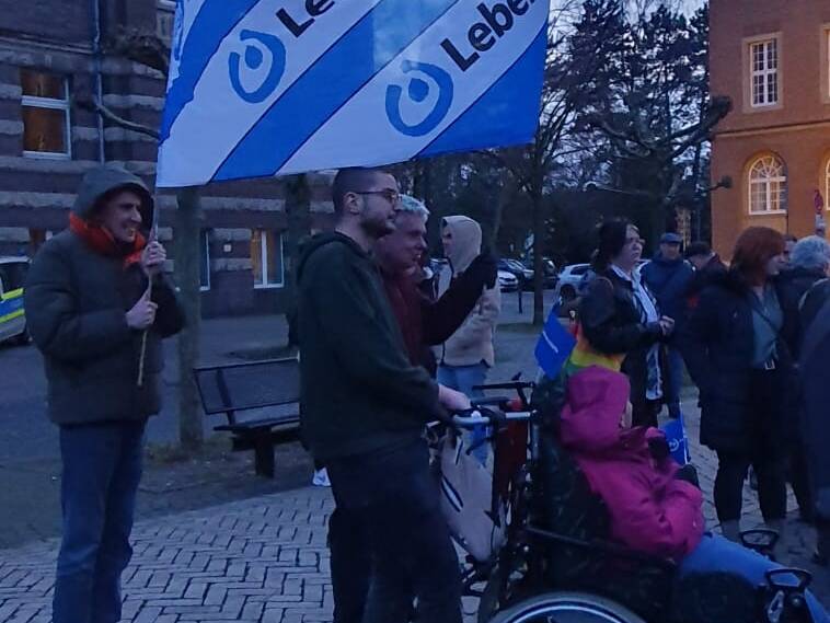 Menschen, draussen mit einer Lebenhilfe Flagge.