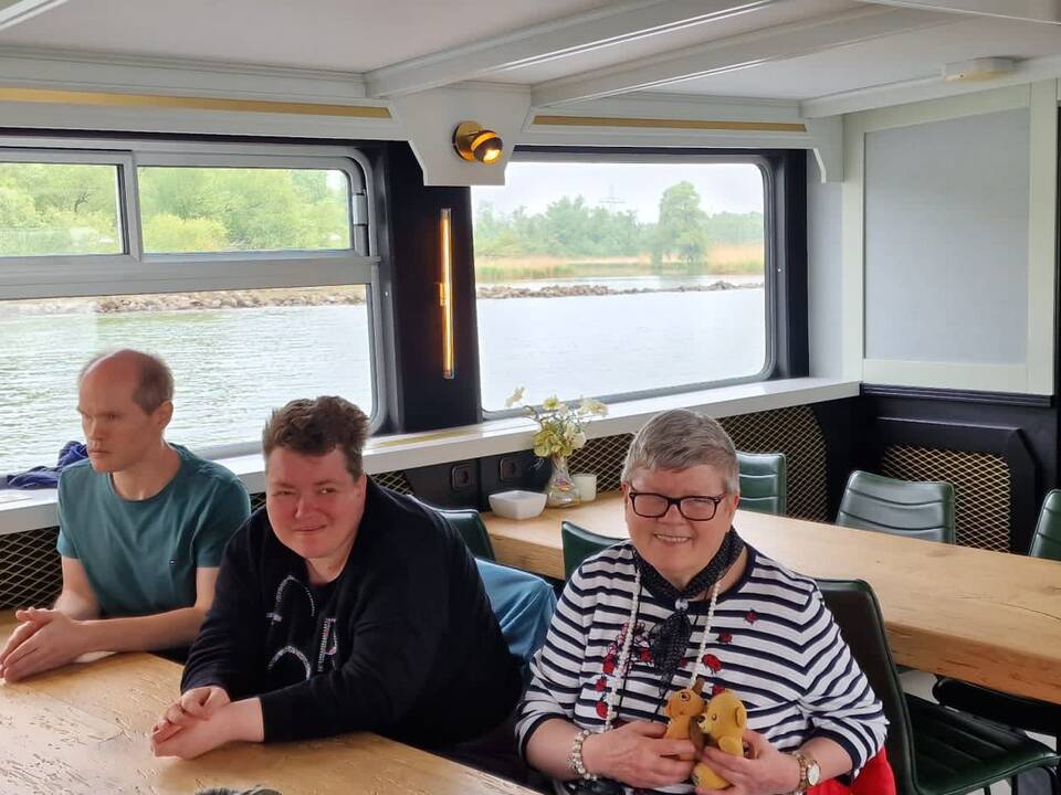 Drei Personen sitzen am Tisch.