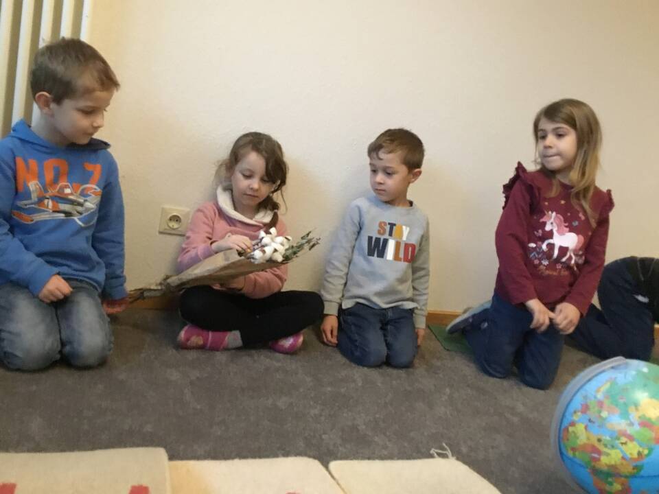 Vier Kinder sitzen in einem Raum auf dem Boden.