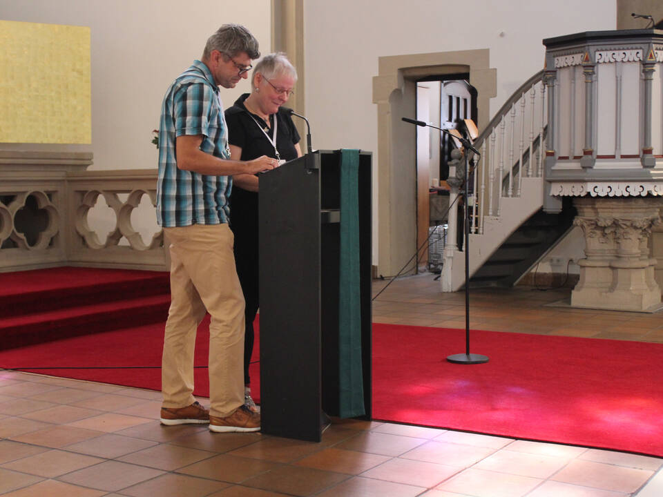 Menschen stehen vor dem Altar und sprechen.