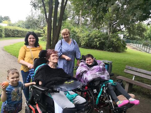 Vier erwachsene Personen und ein Kind, zwei Frauen sitzen im Rollstuhl.