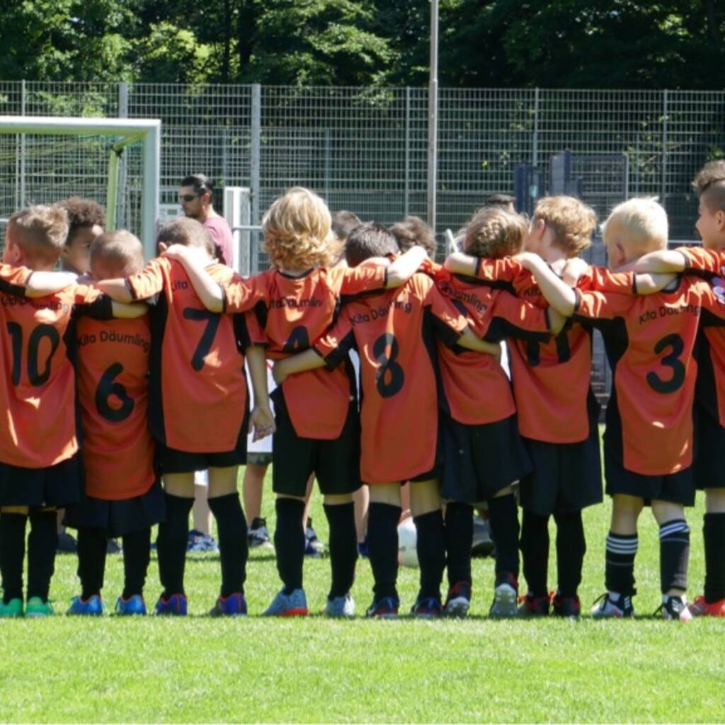 Eine Mannschaft steht mit dem Trainer auf dem Fussballplatz