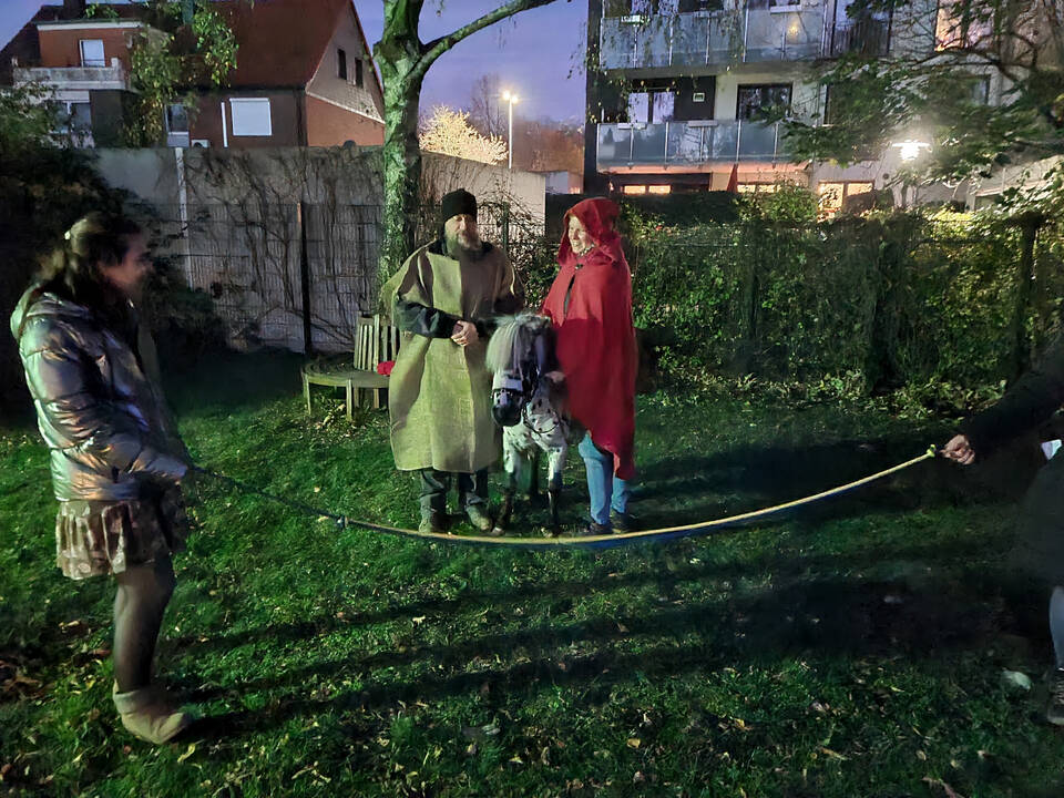 Mehrere Personen stehen auf einer Wiese. Zwei neben einem Pony.