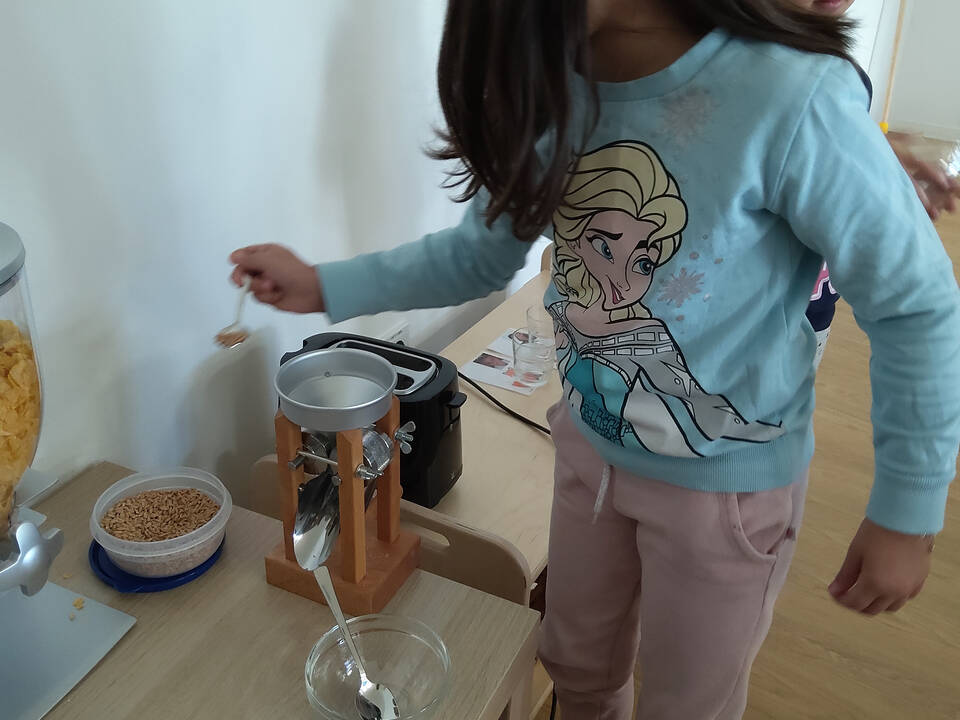 Ein Kind füllt Körner in die Kornquetsche.