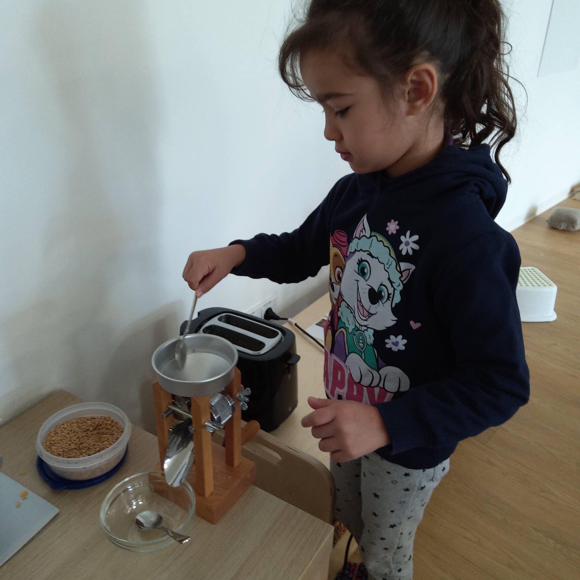 Ein Kind füllt Körner in die Kornquetsche.