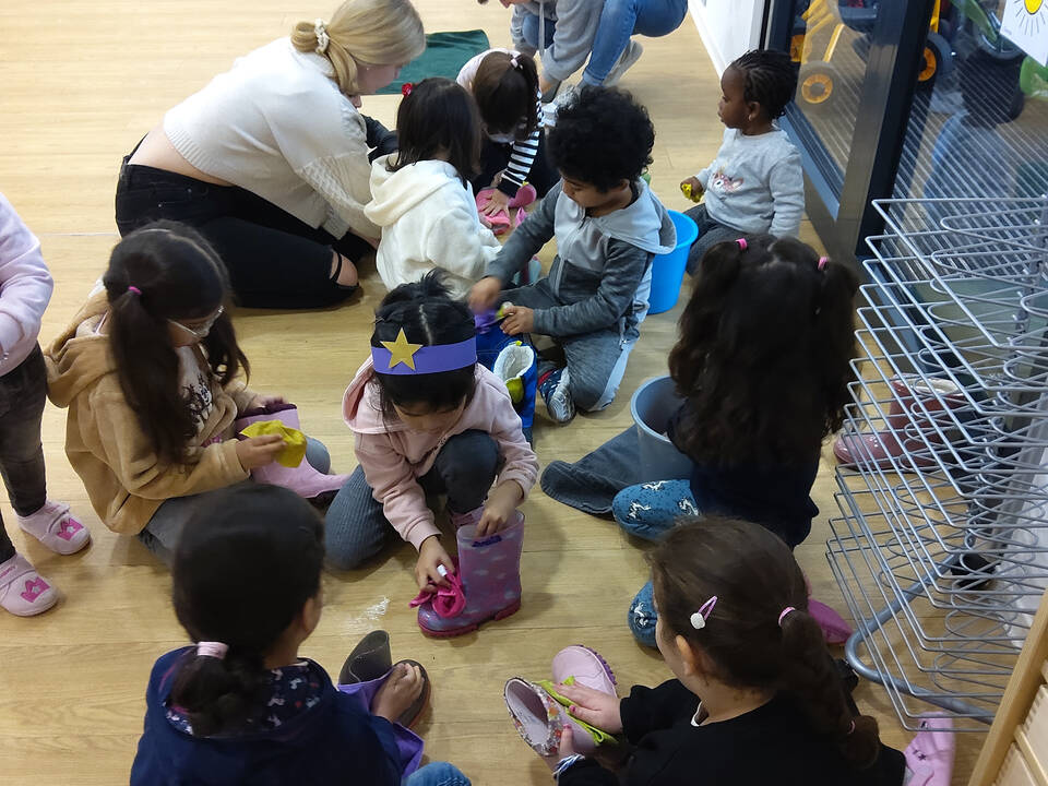 Kinder sitzen auf dem Boden und putzen ihre Stiefel.