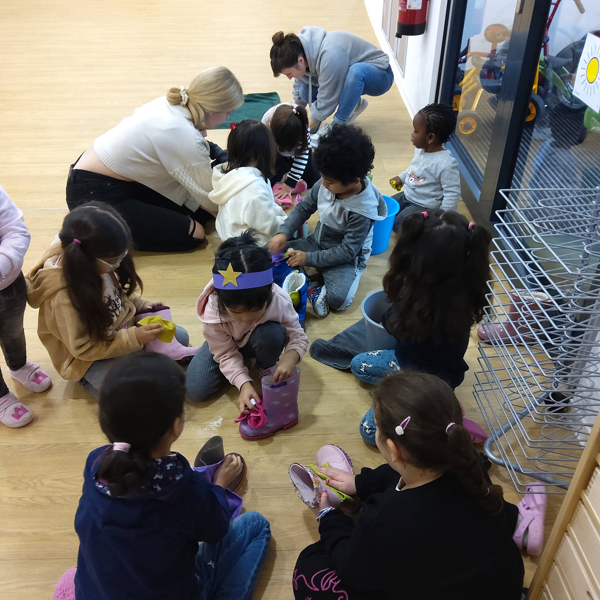 Kinder sitzen auf dem Boden und putzen ihre Stiefel.