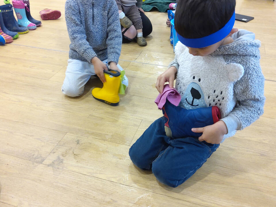 Zwei Jungs sitzen auf dem Boden und putzen ihre Stiefel.