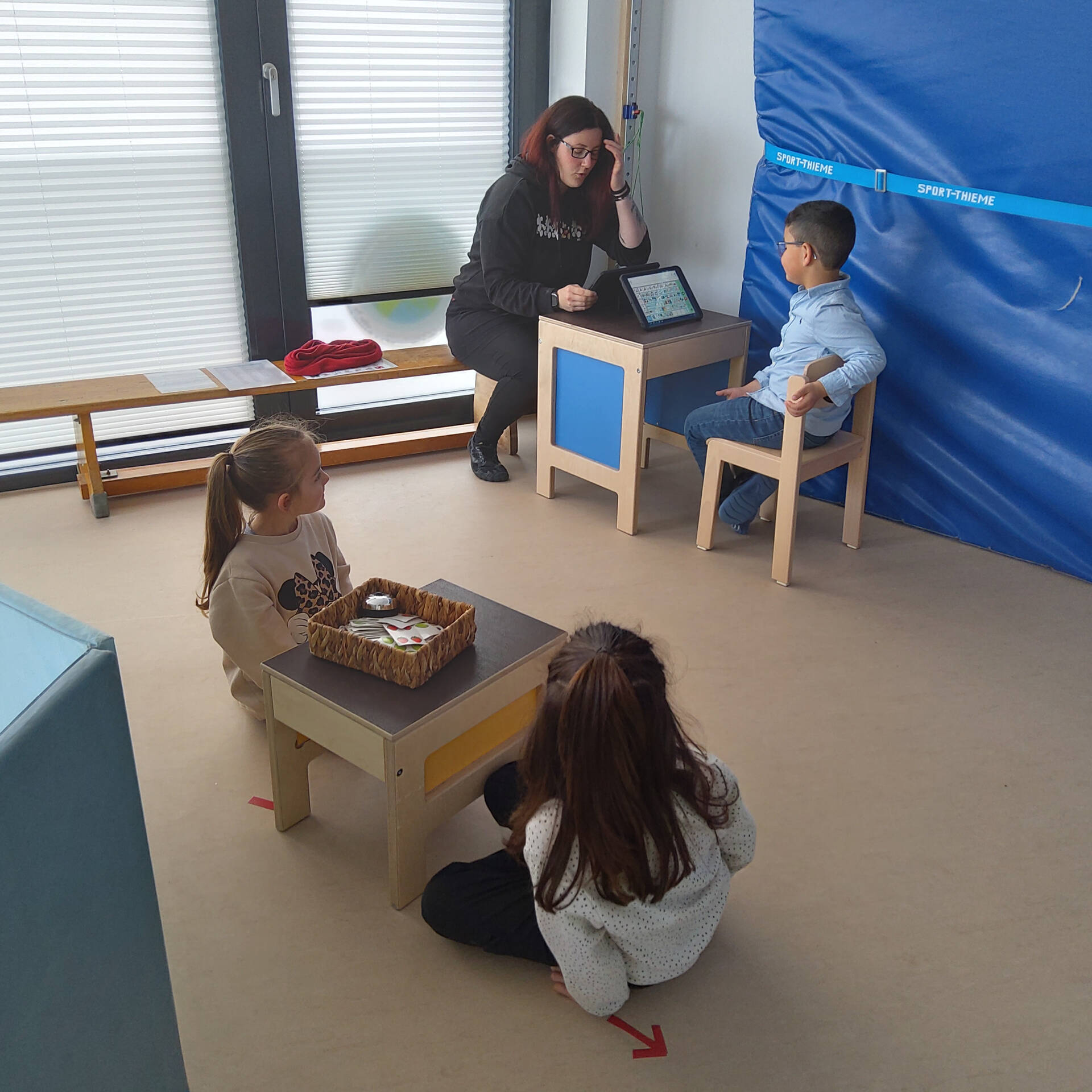 Kinder sitzen an kleinen Tischen.