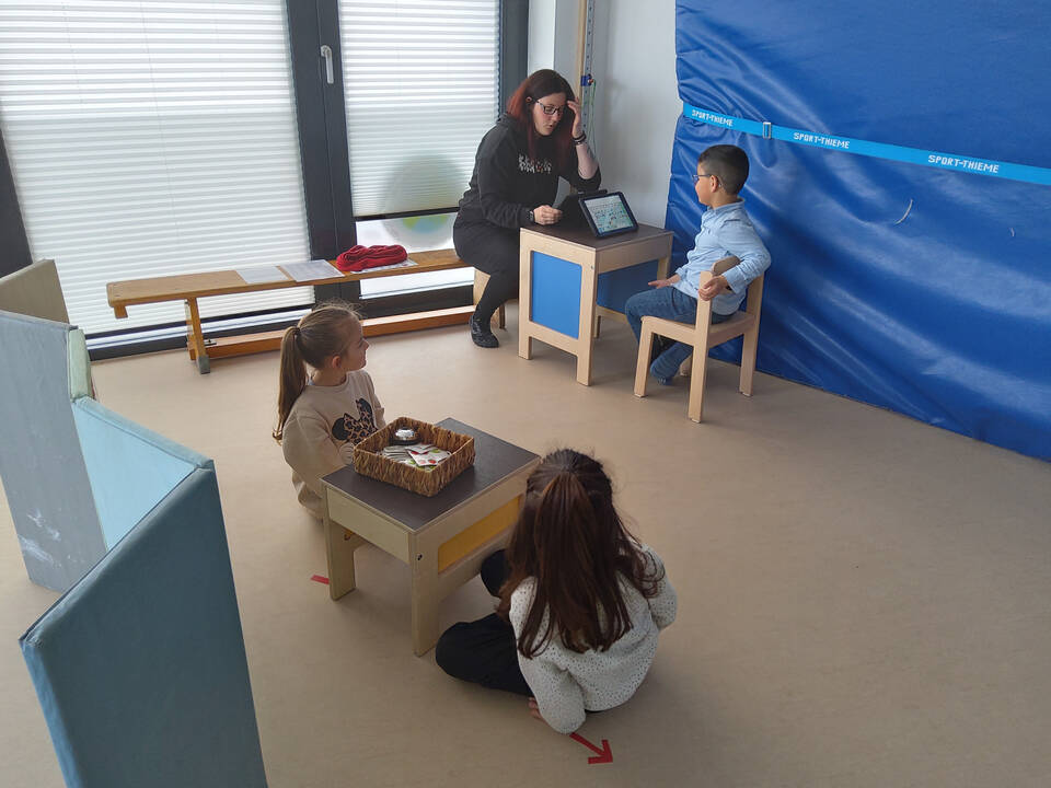 Kinder sitzen an kleinen Tischen.