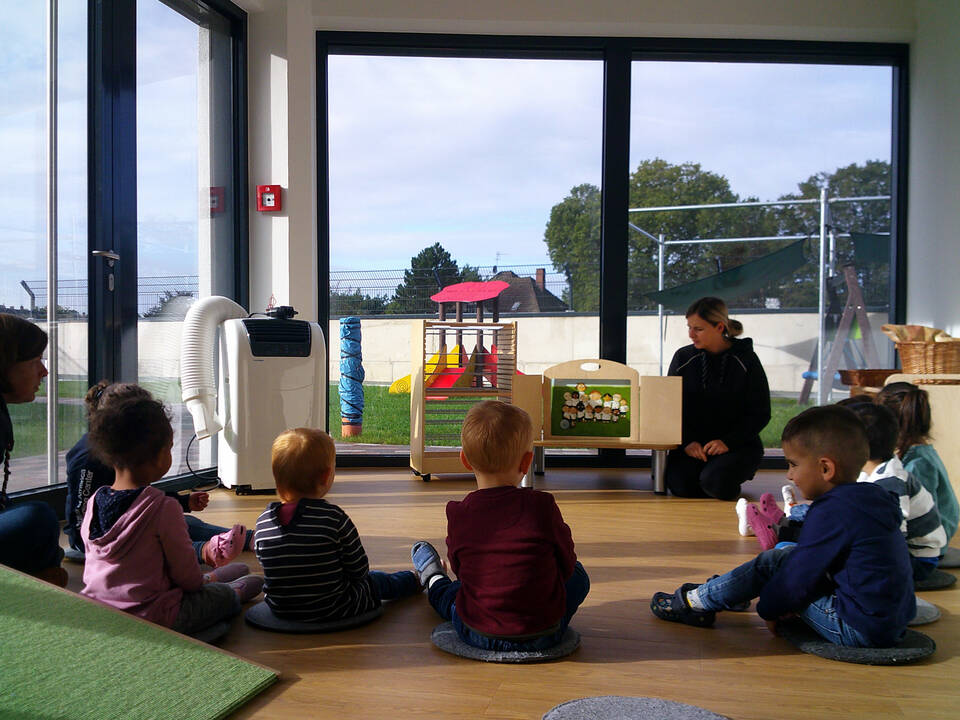 Kinder schauen auf Bilder die eine Frau zeigt.