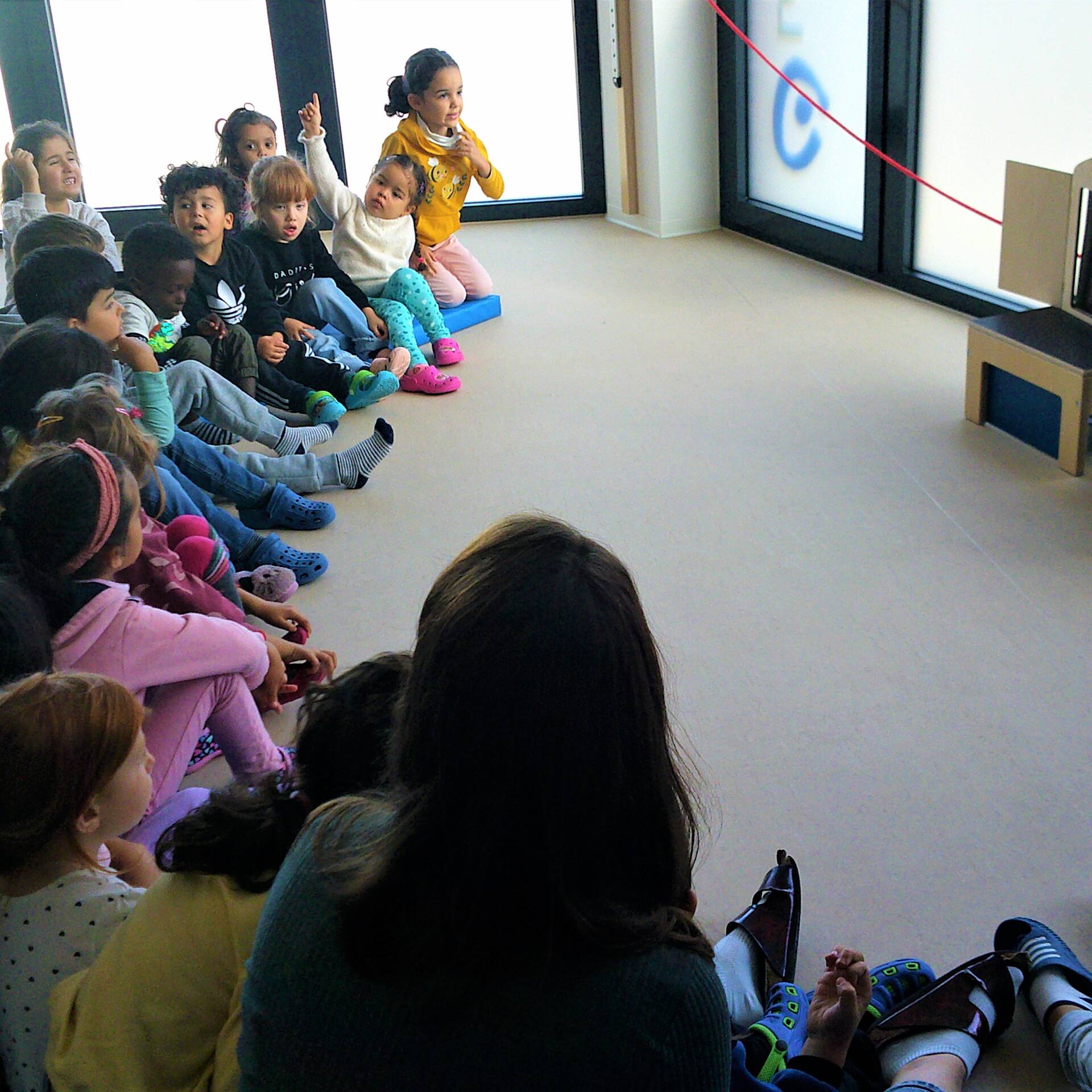 Kinder sitzen auf dem Boden im Halbkreis