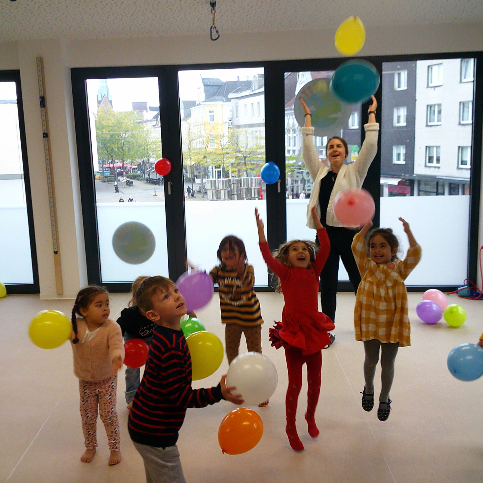 Kinder spielen innen mit Luftballonen.