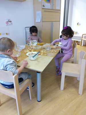 Drei Kinder sitzen am Tisch und dekorieren Plätzchen.