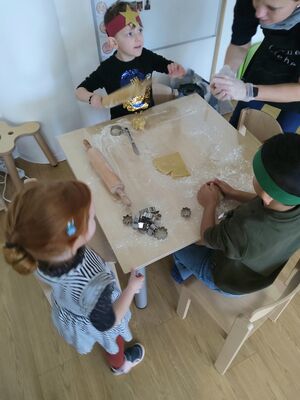 Kinder stechen am Tisch Plätzchen aus.