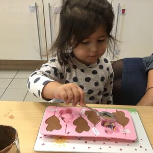Ein Kind füllt eine Kuchenform mit Schokolade