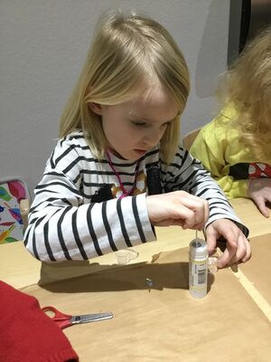 EIn Mädchen klebt einen Kerzendochte ein.
