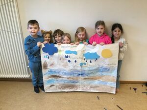 Einige Kinder halten ein großes Plakat in den Händen.