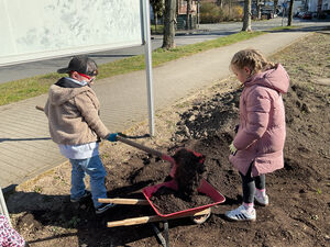 Zwei Kinder befüllen eine Schubkarre