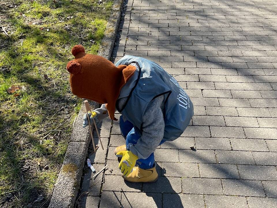 Ein Kind hebt Müll mit einer Zange auf.