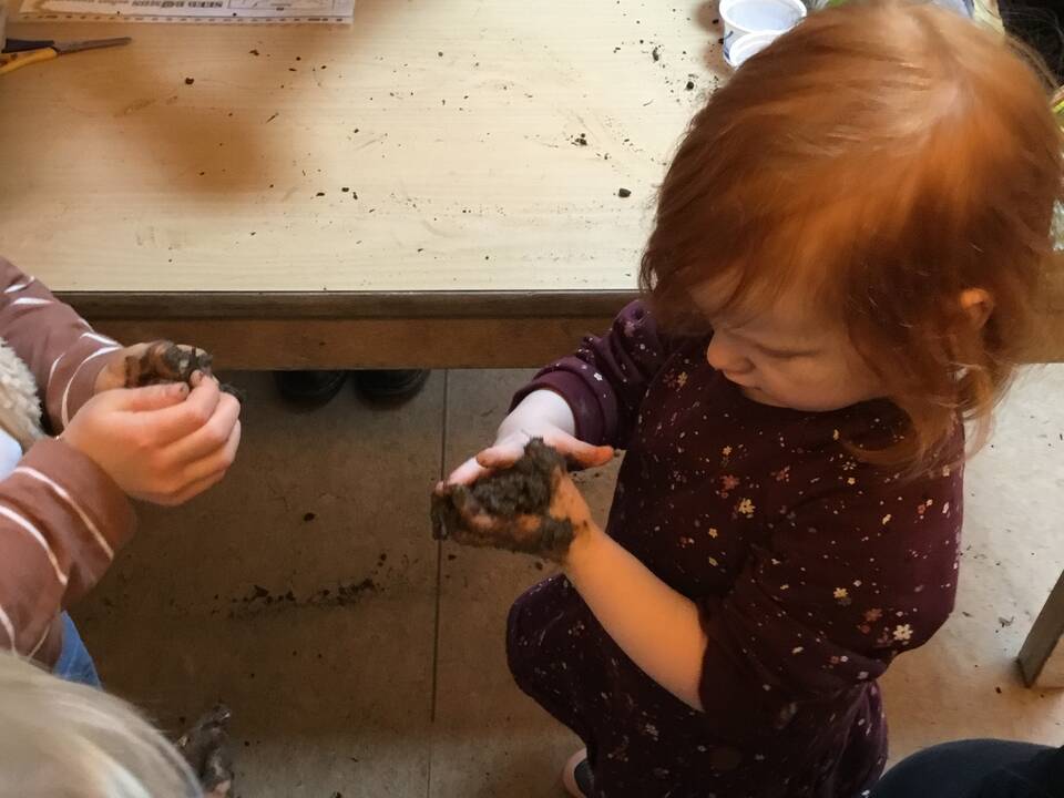 Ein Mädchen formt in den Händen Erde.