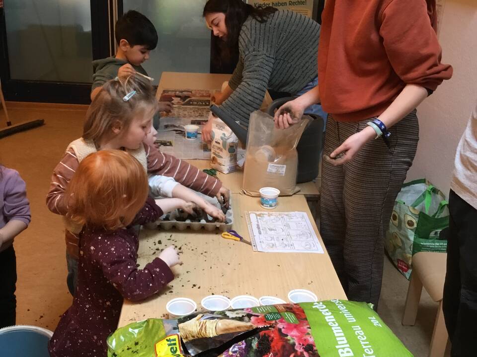 Kinder befüllen Eierkartons mit Erde.