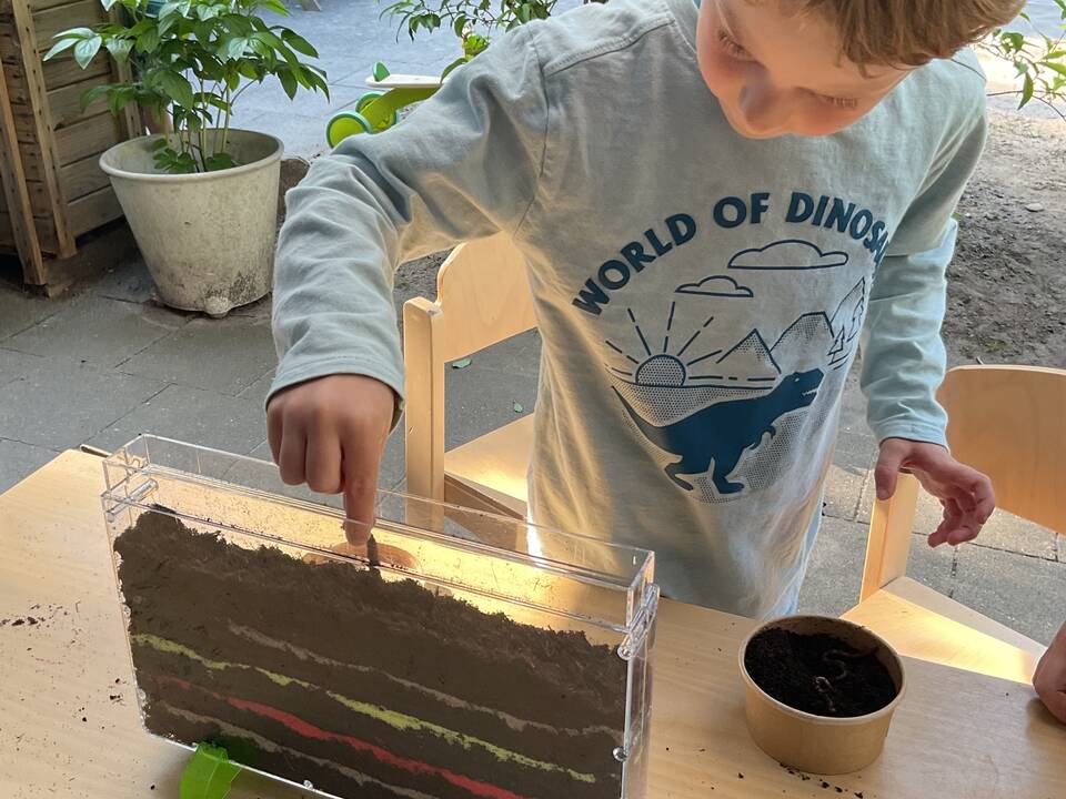 Ein Kind befüllt ein Terrarium.