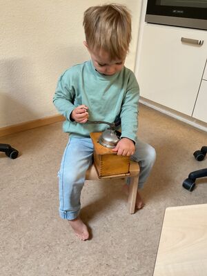 Ein Kind mahlt Kaffe in einer Kaffeemühle.