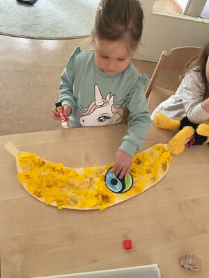 Ein Kind klebt ein faire trade Zeichen auf eine gebastelte Banane