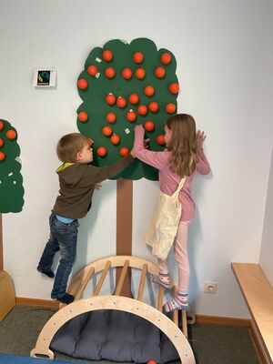 Kinder pflücken künstliche Äpfel von einem künstlichen Baum