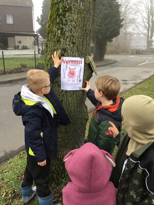 Kinder hängen die Vermisstenanzeige an einem Baum auf.