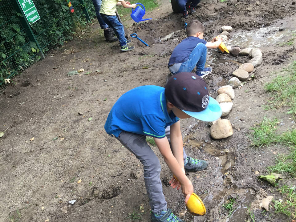 Mehrere Kinder und ein Erwachsener sind draussen.
