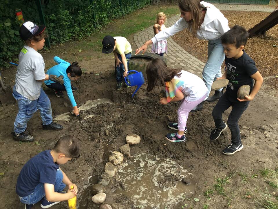 Kinder spielen und graben im Matsch.