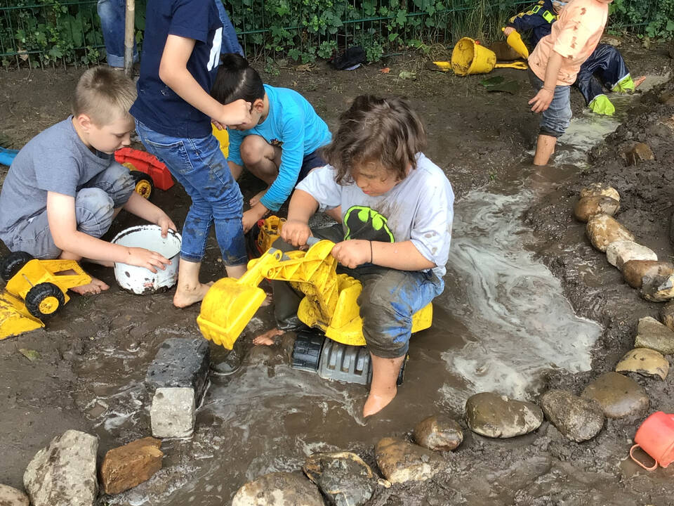 Mehrere Kinder stehen und spielen im Matsch.
