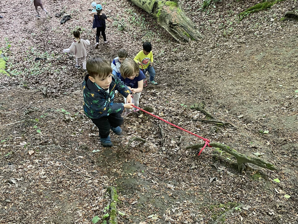 Kinder ziehen sich an einem Seil hoch.