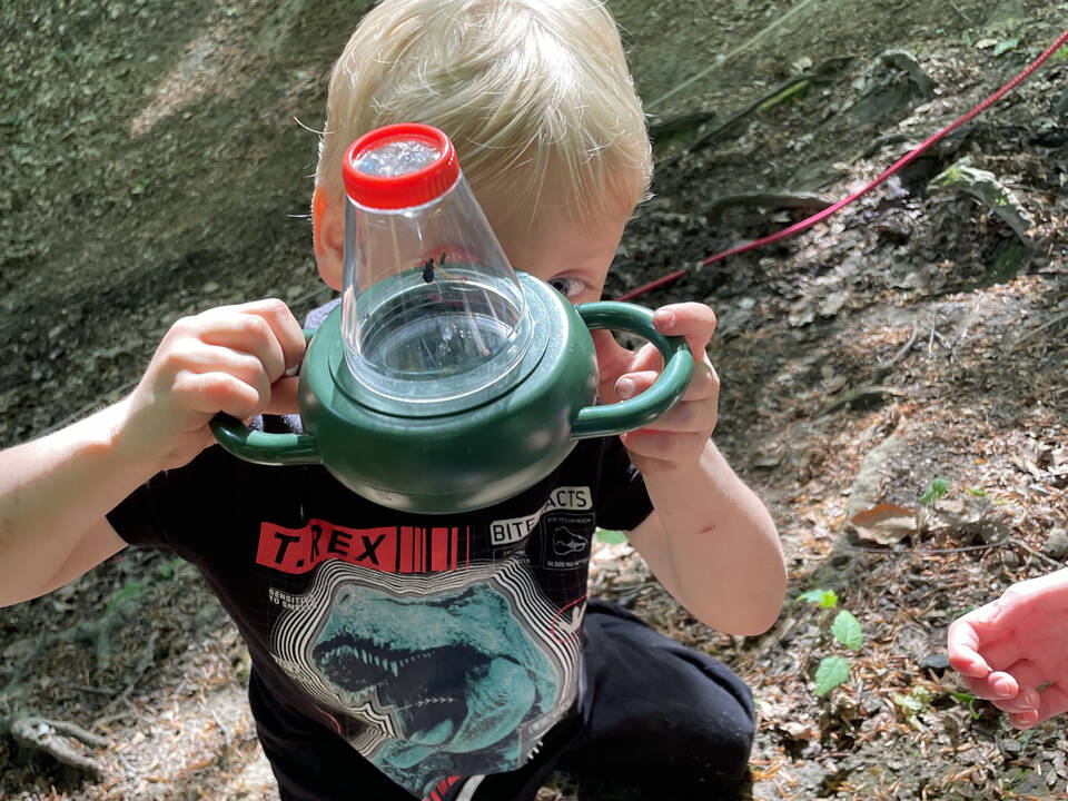 Ein Kind schaut in ein Lupenglas.