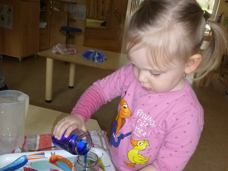 Ein Kind füllt gefärbtes Wasser um.