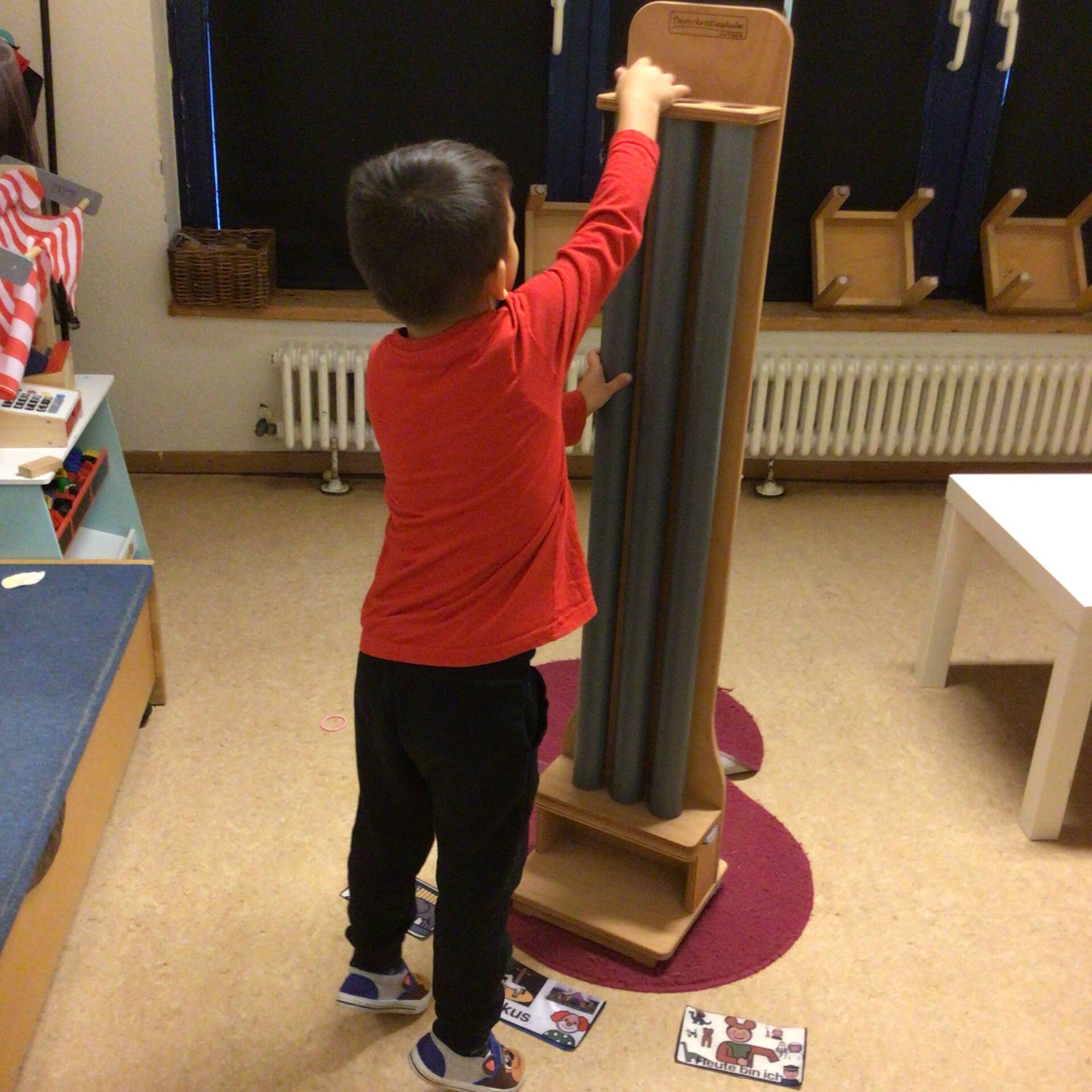 Ein Kind schmeisst etwas ganz links in eine Röhre.