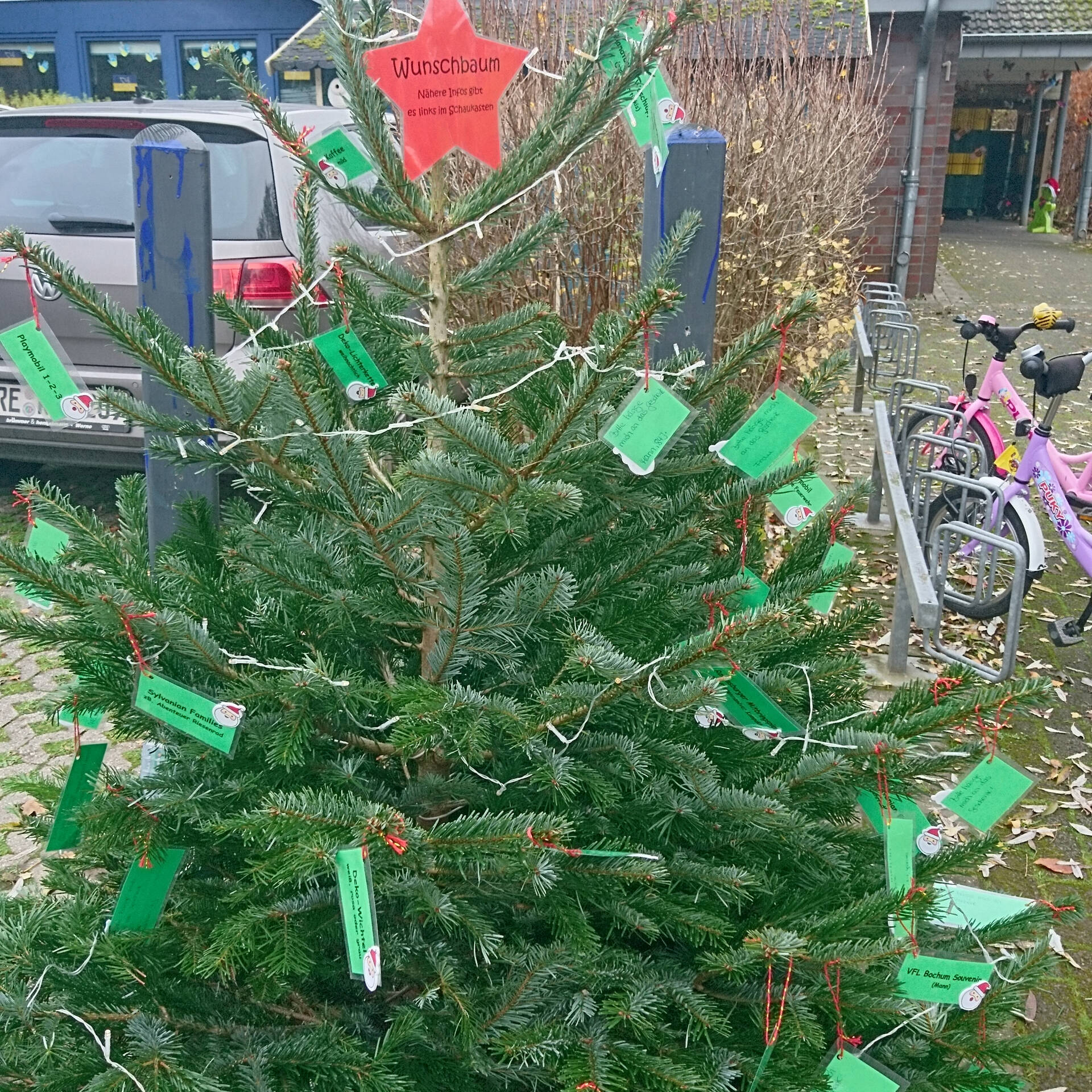 Ein Tannenbazm mit einem roten Stern, einer Lichterkette und vielen grünen Zetteln.