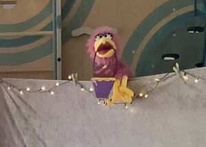 Eine Handpuppe mit einem Pappeimer im Schnabel