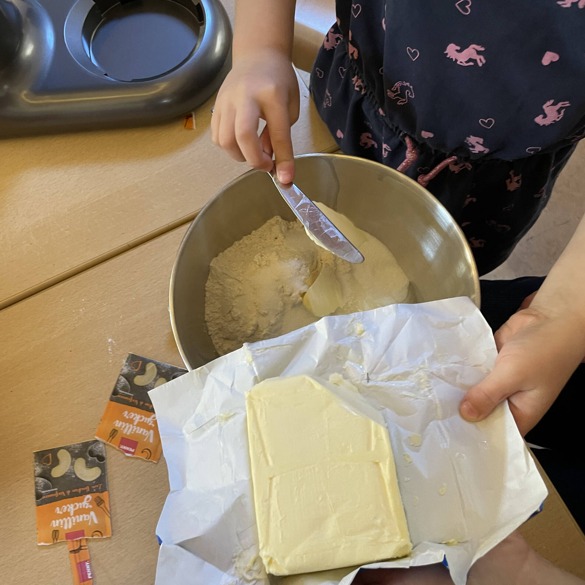 Kinderhände fügen Butter in eine Schüssel mit Zutaten.