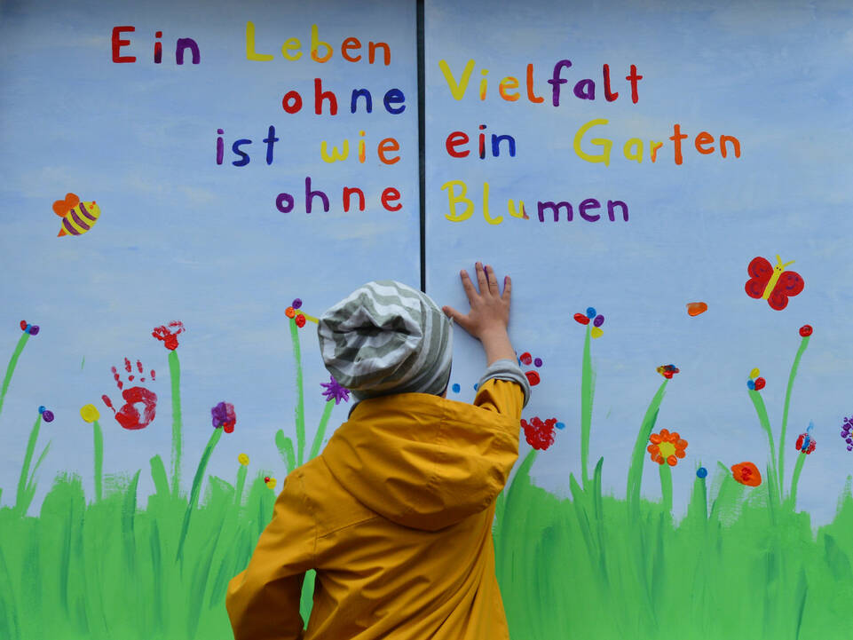 Ein Kind drückt seine Hand auf ein großes Fensterplakat